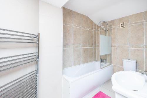 a bathroom with a tub and a toilet and a sink at DAGENHAM 3 and 4 BEDROOMS 2BATHS with Parking in Dagenham