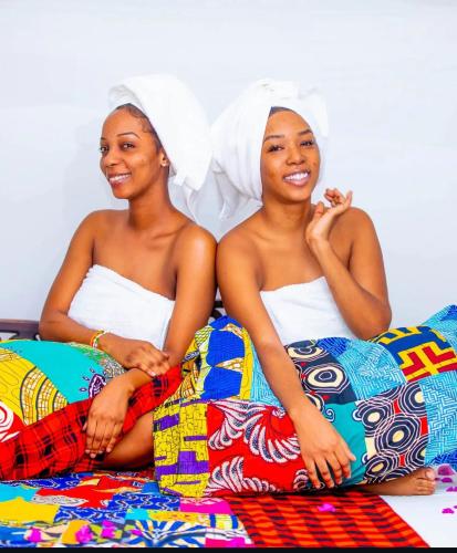two women in towels sitting on a bed at Kiota jungle homestay in Dar es Salaam
