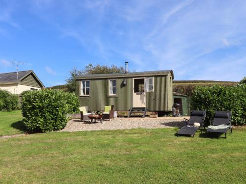 a green tiny house in a yard at Shepherds Joy in Crediton