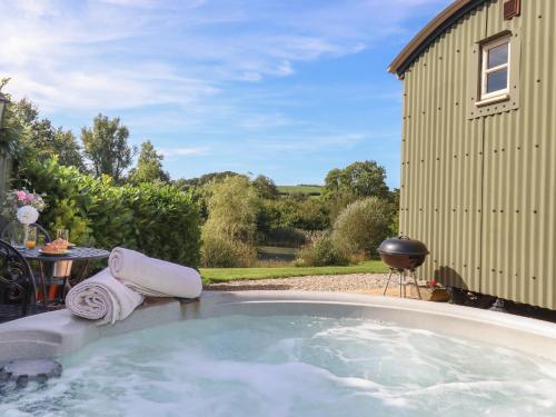 a hot tub in a yard next to a building at Shepherds Joy in Crediton