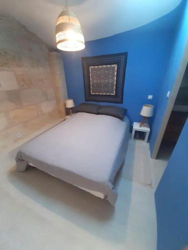 - une chambre bleue avec un lit blanc dans l'établissement Maison d'artiste, à Saint-Quentin-de-Baron