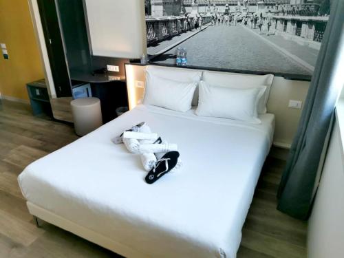 a white bed with a pair of shoes on it at B&B Hotel Roma Fiumicino Aeroporto Fiera 2 in Fiumicino