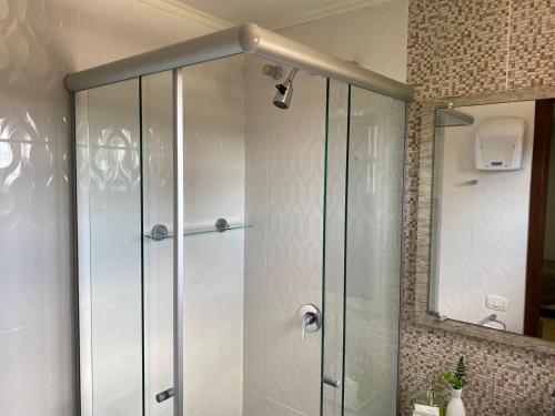 a shower with a glass door in a bathroom at Pousada dos Pássaros in Gramado