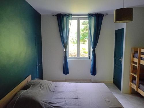a bedroom with a bed and a window with blue curtains at gîte appartement complet jusque 6 personnes in Cruis