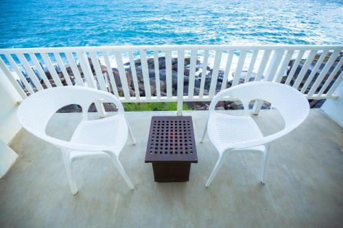 two chairs and a table on a balcony with the ocean at Hotel Zeilan Sunset Point in Unawatuna