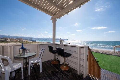 a patio with a table and chairs and the beach at מבנים בים 77 Suites at sea in Haifa