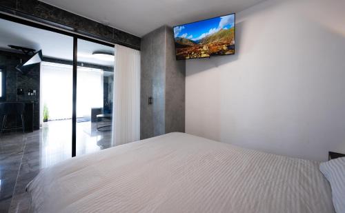 a bedroom with a white bed and a tv on the wall at מבנים בים 77 Suites at sea in Haifa