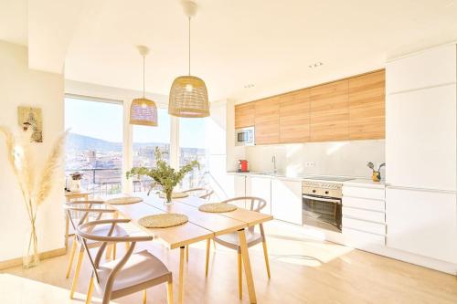 une cuisine avec une table et des chaises et une cuisine avec des armoires blanches dans l'établissement El mirador de Plasencia by keyhom, à Plasence