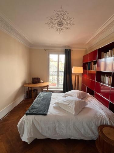 une chambre avec un lit, une table et une fenêtre dans l'établissement Vivre au Village des Batignolles, à Paris