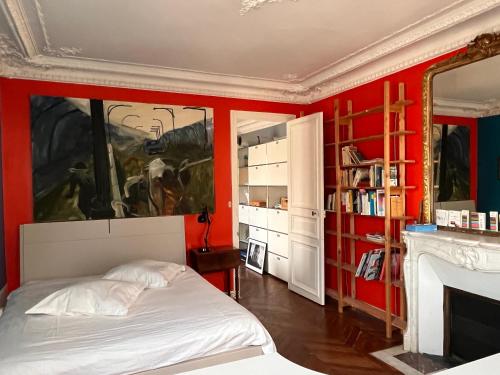 - une chambre avec des murs rouges, un lit et un miroir dans l'établissement Vivre au Village des Batignolles, à Paris