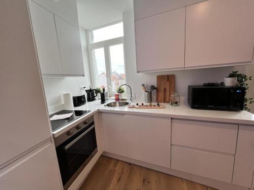 une cuisine blanche avec un évier et un micro-ondes dans l'établissement Gambetta, à Malo-les-Bains