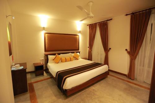 a bedroom with a large bed with yellow pillows at Refresh Hotel Hikkaduwa in Hikkaduwa
