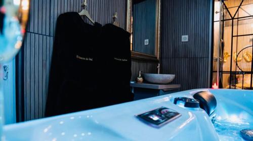 Un baño con bañera y una camisa negra en un perchero. en Loveroom 50 nuances de bulles jacuzzi et sauna privatif, en Lens