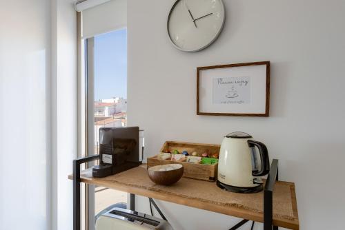 a clock on a wall above a table with a blender at Burgau Village and Sea in Burgau