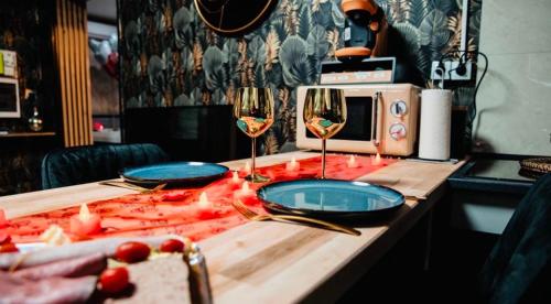 una mesa con dos copas de vino y un microondas en Loveroom 50 nuances de bulles jacuzzi et sauna privatif, en Lens