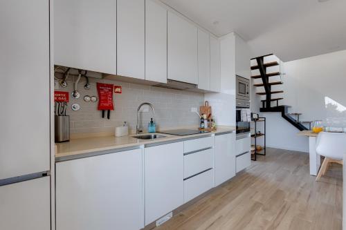 a kitchen with white cabinets and a staircase at Burgau Village and Sea in Burgau