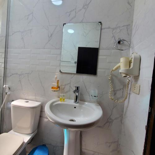 a white bathroom with a sink and a phone at Summit Hotel in Petra