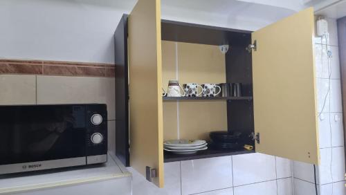 a kitchen with a microwave and a cabinet with dishes at Feeria National Parc in Bucharest
