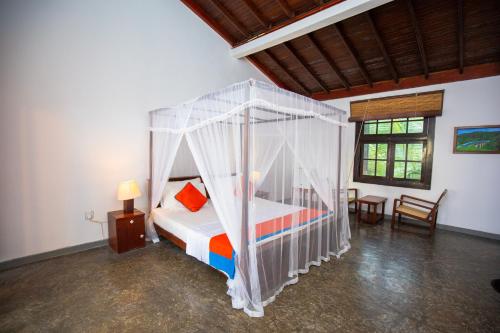 a bedroom with a white canopy bed in a room at Hotel Zeilan Sunset Point in Unawatuna