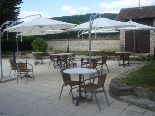 un grupo de mesas y sillas con sombrillas blancas en Chambres d'hôtes la Chaumière, en Arcy-sur-Cure