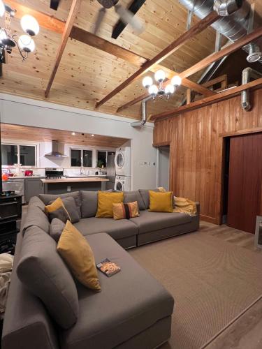 a living room with a gray couch and a kitchen at Birkswyld waterfront cottage Mary Lake in Huntsville