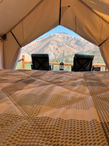a bed in a tent with two chairs in it at Tent 1 Oxen-Le-Fields Montana in Sula