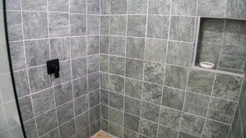 a tiled shower with a black soap dispenser in a bathroom at Divan Eco Lodge in Fortuna