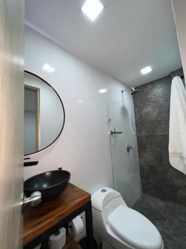 a bathroom with a toilet and a sink and a mirror at Laureles Inn in América