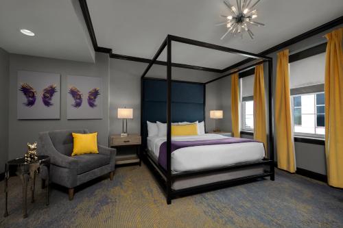 a bedroom with a canopy bed and a chair at The Admiral, Downtown Historic District in Mobile