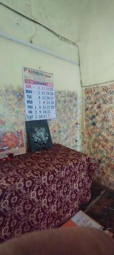 a room with a bed with a calendar on the wall at Viswanatham Guest House in Varanasi