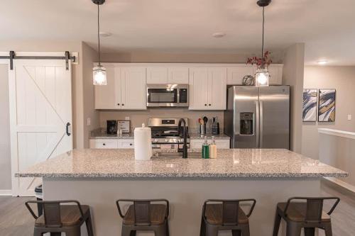 a kitchen with a counter with chairs and a refrigerator at Brand New 2 Bedroom with Office in Loves Park