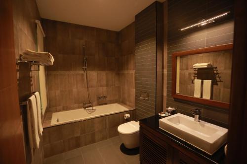 a bathroom with a tub and a sink and a toilet at Refresh Hotel Hikkaduwa in Hikkaduwa