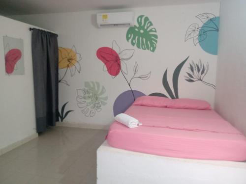 a bedroom with a pink bed and flowers on the wall at Hostal Finca San Martín De Loba in Los Naranjos