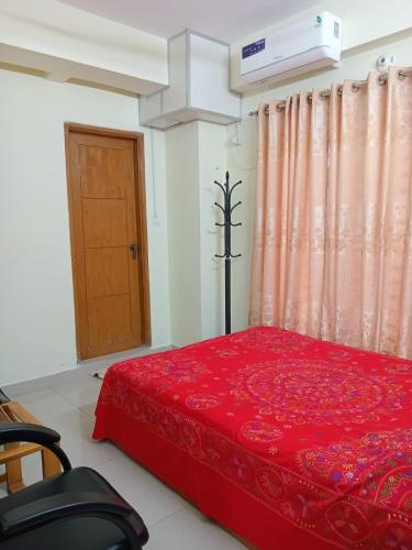 a bedroom with a red bed and a door at Mirpur DOHS in Chak Digun