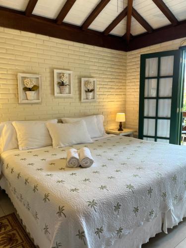 a bedroom with a large bed with two slippers on it at Urikana Boutique Hotel in Teresópolis