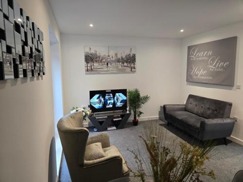 a living room with two chairs and a television at Well-Preserved 2 Bedroom Flat Apartment Around Ricoh Arena-Coventry City FC in Longford