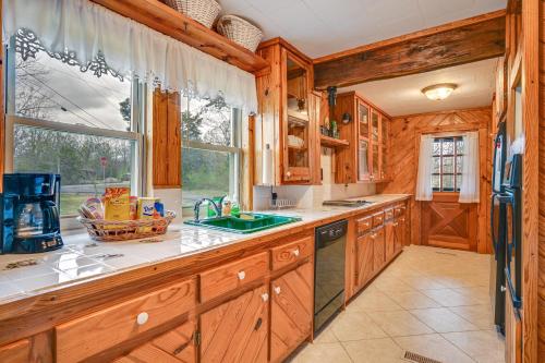 a kitchen with wooden cabinets and a large window at Country Escape Log Cabin Near Kentucky Lake! in Gilbertsville