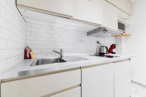 una cucina con mobili bianchi e un lavandino di Studio Confortable proche métro - Saint mandé a Saint-Mandé
