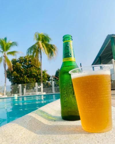 a bottle of beer sitting next to a swimming pool at Club Vacacional COPEN in Tocaima