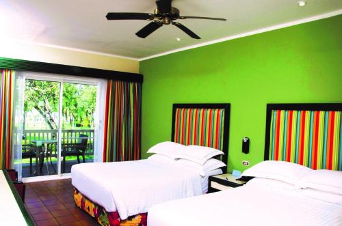 a bedroom with two beds and a green wall at Barceló Tambor - All Inclusive in Tambor