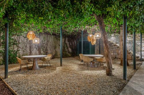a patio with two tables and chairs and a tree at Arrábida Guest House in Setúbal