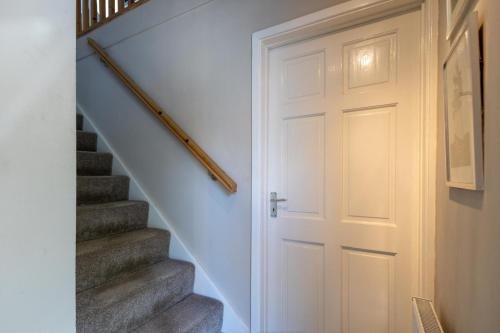 a hallway with a white door and stairs at King Coel in Colchester