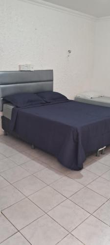 a bed with a blue comforter sitting on a floor at Hotel Recanto da lagoa in Juazeiro do Norte