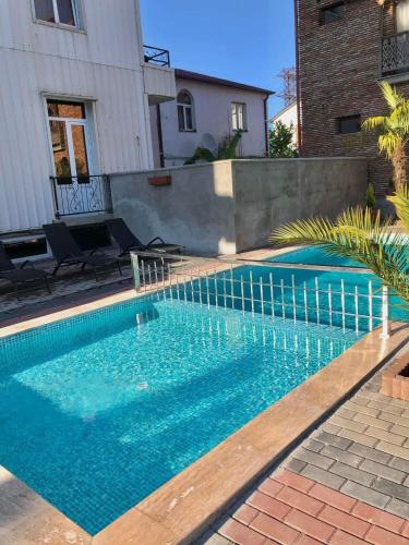 a swimming pool with blue water in front of a house at Hotel Like Mari in P'ichvnari