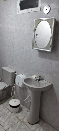 a bathroom with a sink and a toilet and a mirror at Hotel Recanto da lagoa in Juazeiro do Norte