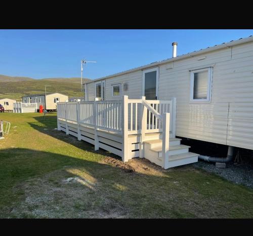 a white mobile home with a porch and stairs at Caravan in Barmouth in Llanddwywe