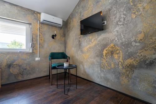 a chair and a table in a room with a wall at Aleks apartmani in Knjazevac.