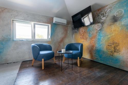 two blue chairs and a table in a room at Aleks apartmani in Knjazevac.