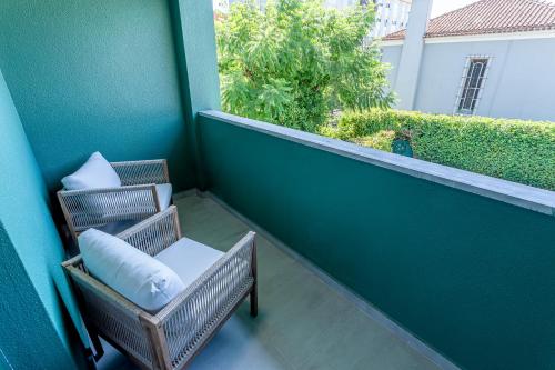 a balcony with two chairs and a window at Arrábida Guest House in Setúbal