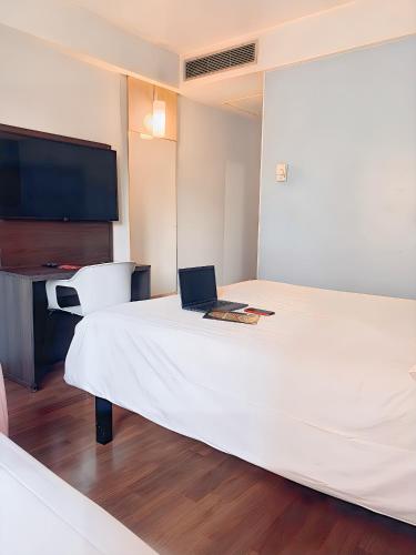 a hotel room with a bed with a laptop on it at ibis Sao Paulo Paulista in Sao Paulo